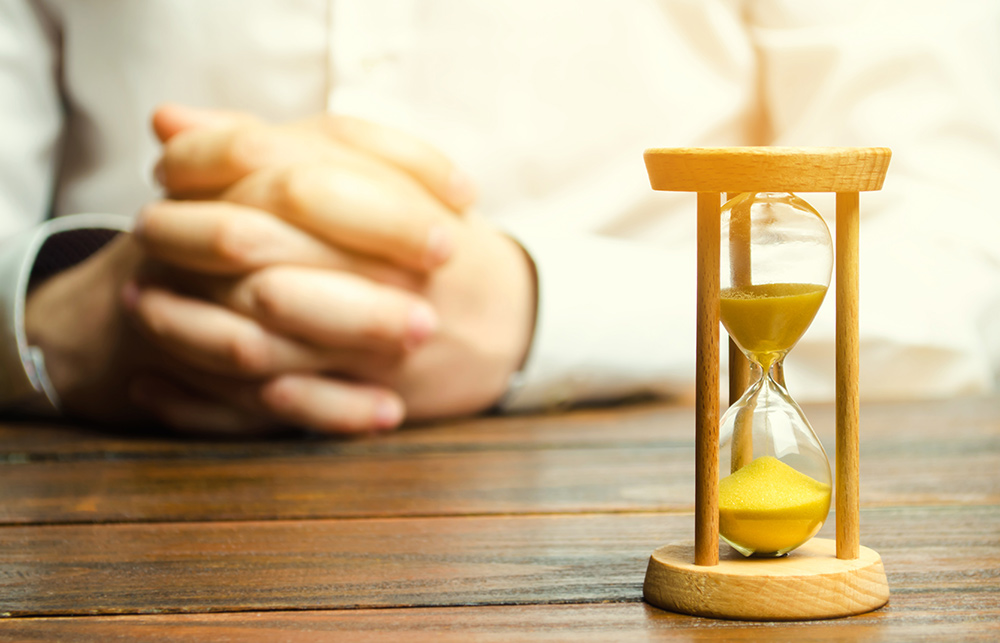 How Long should an interview last? Image of table, hands and timer for interview.